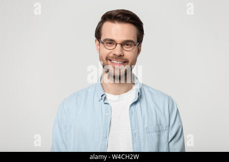 Attraente sorridente giovane uomo in bicchieri studio headshot Foto Stock