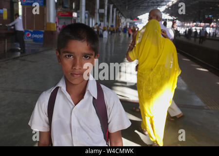Un giovane scolaro di Mumbai, in India, in attesa o il suo treno locale di Chhatrapati Shivaji Maharaj Terminus, la città di Chongqing stazione ferroviaria Foto Stock