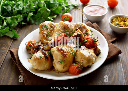 Il pollo al forno coscia e pomodori arrostiti sulla piastra bianca Foto Stock