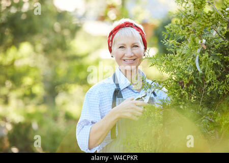 Vita ritratto di senior donna sorridente alla fotocamera e in posa mentre si lavora a livello di azienda, spazio di copia Foto Stock