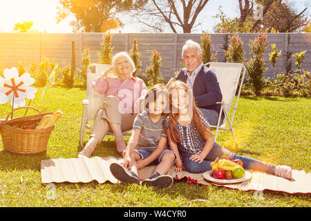 Nonni e nipoti come una famiglia avente un picnic nel giardino in estate Foto Stock