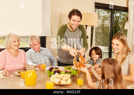 Famiglia estesa con i bambini e i nonni a pranzo a casa a tavola Foto Stock