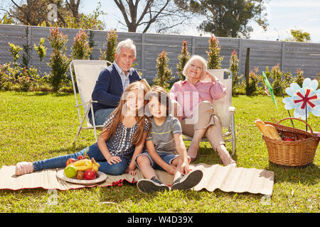 Felice nipoti. Bambini aventi un picnic con i nonni nel giardino in estate Foto Stock
