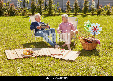 Coppia senior come i pensionati in giardino in estate si rilassa ad un picnic Foto Stock