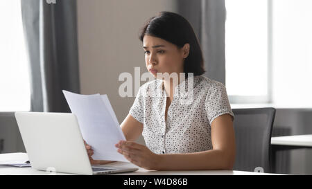 Sottolineato sconvolto asian business donna lettura cattive notizie per la carta Foto Stock