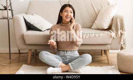Ragazza asiatica comunicante con un amico, parlando al telefono Foto Stock
