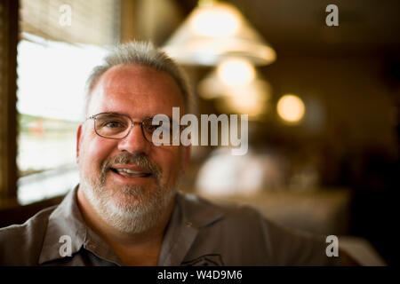 Ritratto di un sorridente barbuto uomo maturo con gli occhiali. Foto Stock