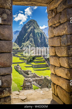 Le rovine Inca di Machu Picchu, Sito Patrimonio Mondiale dell'UNESCO attraverso il telaio del muro di pietra Foto Stock