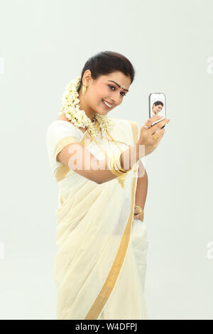 South Indian woman taking picture of herself with a mobile phone Stock Photo