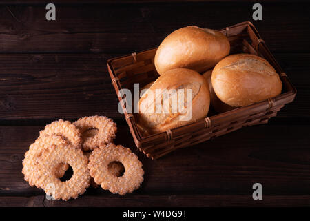 Biscotti fatti in casa e panini nel cestino del pane su un sfondo di legno, chiave di basso, rustico Foto Stock