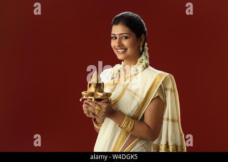 Sud donna indiana tenendo un kalash e sorridente Foto Stock