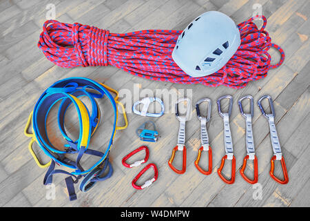 Concetto di imballaggio di arrampicata sportiva marcia per un viaggio. Casco, corda, cablaggio dispositivo di assicurazione, moschettoni, quickdraws su sfondo di legno. Foto Stock