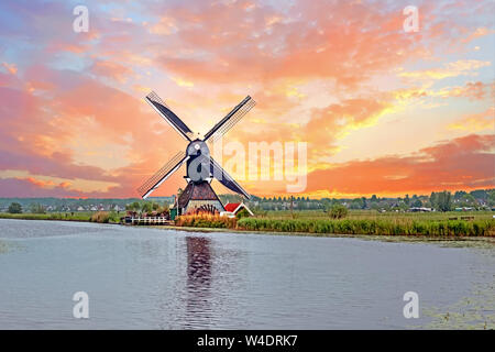 Antenna a partire da un tradizionale mulino a vento in campagna a Kinderdijk nei Paesi Bassi al tramonto Foto Stock