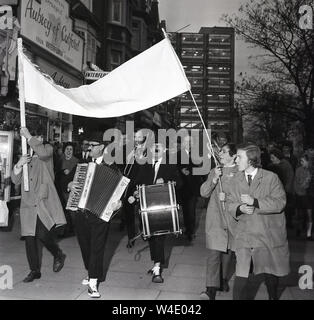 Anni sessanta, storico, commedia stelle del pannello della radio gioco, "La squadra pensa a piedi verso il basso a South London street prima di apparire il Teatro Savoy, Catford, Londra, Inghilterra, Regno Unito. Il popolare gioco del pannello, una parodia di " Domande " è stato svolto per la ride e ha funzionato per quasi vent'anni. Foto Stock