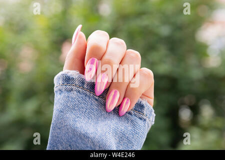 Mano femmina con una bella rosa manicure. Foto Stock