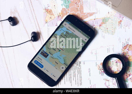 Nizhyn, Ucraina/Luglio-16-2019: Smartphone con Google Map applicazione avviata giacente sulla mappa. Viaggio, destinazione, di ricerca di un percorso del concetto. Foto Stock