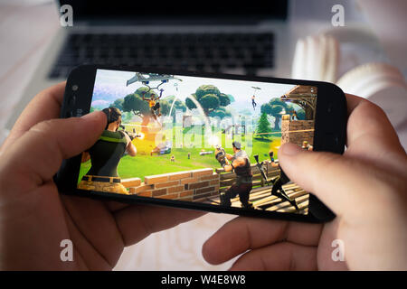 Nizhyn, Ucraina/Luglio-16-2019: mani tenendo lo smartphone e la riproduzione di Fortnite. Android il concetto di gioco. Foto Stock