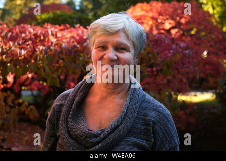 Close up ritratti di senior donne anziane, Bright Foglie rosse di sfondo Foto Stock