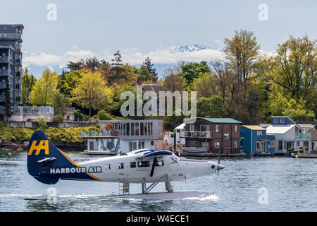 Porto idrovolante aria di rullaggio per il decollo fuori del centro cittadino di Victoria con alberi e montagne coperte di neve in background. Foto Stock