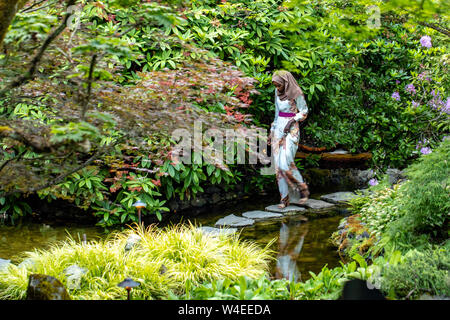 Donna che cammina nel giardino giapponese ai Giardini Butchart - Brentwood Bay, vicino a Victoria, Isola di Vancouver, British Columbia, Canada Foto Stock