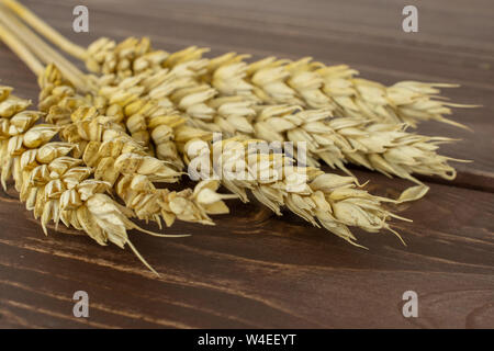 Sacco di tutta la golden grano di pane orecchio sul legno marrone Foto Stock