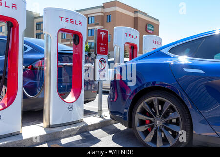 Blue Tesla Model S e la Tesla Model X di Tesla Supercharger su una luminosa giornata di sole. Foto Stock