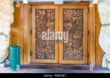 Il legno intagliato a mano delle porte anteriori della Madonna Inn a San Luis Obispo, California. Le sculture sono di grappoli di uva sulla vite. Foto Stock