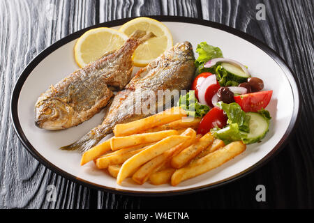 Adriatico fried Sarpa salpa il pesce con il limone servita con verdura fresca insalata e patatine fritte close-up su una piastra sul tavolo orizzontale. Foto Stock