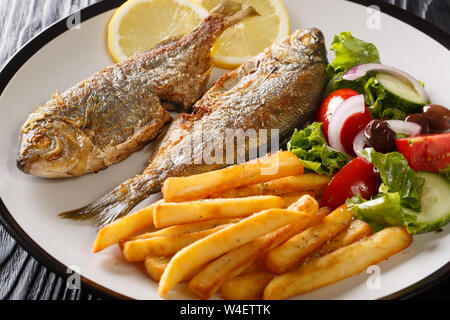 Porzione di frittura di salpe porgy pesce con limone e verdura fresca insalata di close-up su una piastra sul tavolo orizzontale. Foto Stock