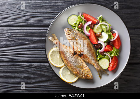 Fresche fritte Sarpa salpa pesci con estate insalata di verdure e limone close-up su una piastra sul tavolo. parte superiore orizzontale vista da sopra Foto Stock