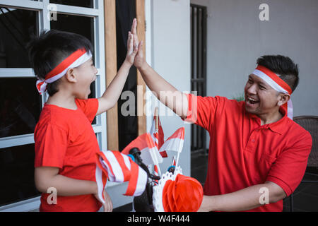 Padre e figlio di alta cinque mentre la decorazione di noleggio Foto Stock