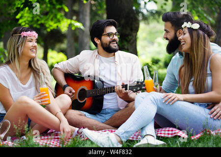 Estate, vacanze, la musica e il tempo libero concetto. Gruppo di amici hanno picnic all'aperto. Foto Stock