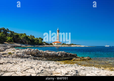 Croazia, isola di Dugi Otok, bellissimo vecchio faro di Veli Rat sulla pietra a riva tra i pini Foto Stock