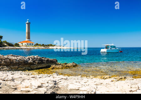 Croazia, isola di Dugi Otok, bellissimo vecchio faro di Veli Rat sulla pietra a riva tra i pini Foto Stock