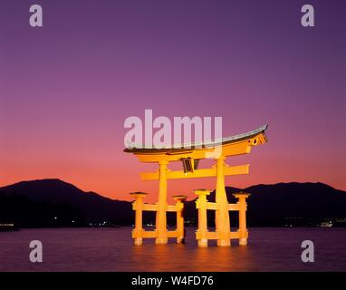 Giappone, Honshu, Hiroshima, l'isola di Miyajima, santuario di Itsukushima, vista al tramonto di illuminati Porta Torii Foto Stock