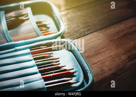 Blunt matita colorata in un caso a matita su una scrivania di legno in un tetro luce. concetto di istruzione, infanzia e creatività Foto Stock