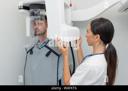 Bel uomo paziente in piedi nella macchina a raggi x. Radiografia panoramica di professional dental clinic. Foto Stock