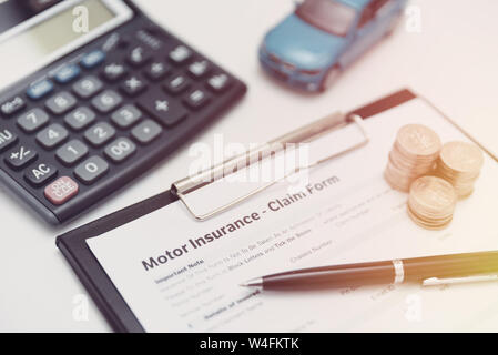 Motore o assicurazione auto claim form con moneta della pila, calcolatrice e modello di auto. Foto Stock
