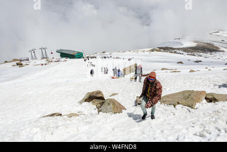 I turisti e gli estrattori di slittino arrampicata neve paesaggio riempito in Gondola Gulmarg Fase 2 / Apharwat picco, Gulmarg, Jammu e Kashmir India Foto Stock