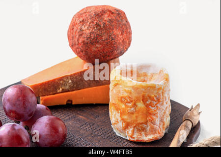 Delicatessen formaggi piccanti di diverse varietà. Rosso cheddar, blu Dor, piramide, Stilton, Belper-Noll su un pannello di ceramica marrone con uve. Piccante Foto Stock