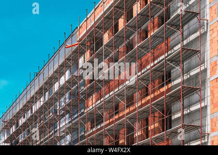 Ponteggio a vuoto in un cantiere con incompiuto edificio incompleto e cielo vuoto come spazio di copia Foto Stock