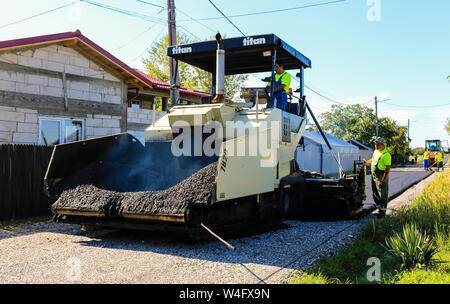 Sibiu, Romania - 2019. Lavoratori che operano asfalto lastricatore macchina durante la costruzione di strade. La costruzione di una nuova strada con il supporto dalla Europea Foto Stock
