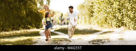 Felice ragazza acceso dai suoi genitori, avente picnic in campagna Foto Stock