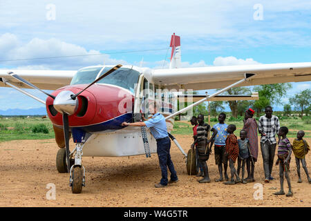 In Uganda, Karamoja, Kotido, MAF Mission Aviation Fellowship, sbarcati aeroplano a bush pista di atterraggio per aerei, pilota e curiosi tribù Karamojong, servizio di volo per i missionari, ONG e beni di emergenza Foto Stock