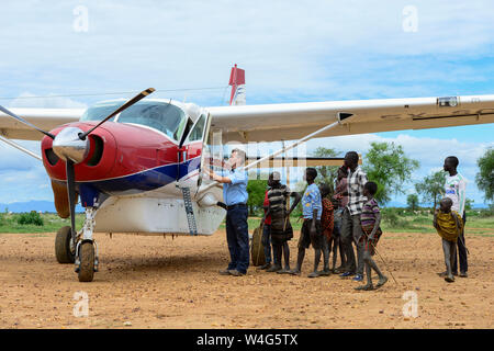 In Uganda, Karamoja, Kotido, MAF Mission Aviation Fellowship, sbarcati aeroplano a bush pista di atterraggio per aerei, pilota e curiosi tribù Karamojong, servizio di volo per i missionari, ONG e beni di emergenza Foto Stock