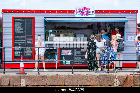A North Berwick, East Lothian, Scozia, Regno Unito, 23 luglio 2019. Regno Unito: Meteo inizio di una ondata di caldo porta i visitatori alla East Lothian costa. Il Lobster shack nel porto è occupato a pranzo Foto Stock
