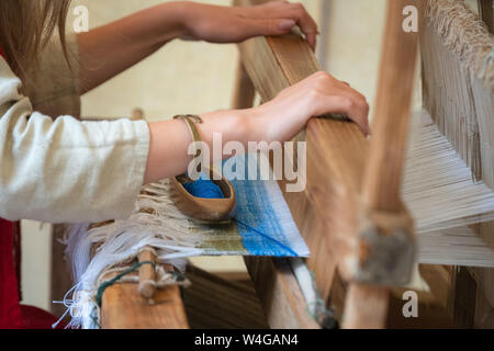 Close up donna mani tessitura di blu e bianco pattern sul telaio. Tradizionale tecnica di tessitura Foto Stock