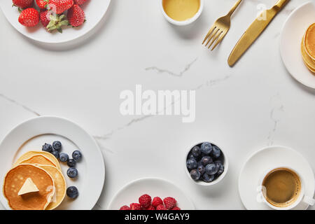 Vista superiore della gustosa prima colazione con pancake, miele, diversi tipi di frutti di bosco e la tazza di caffè Foto Stock