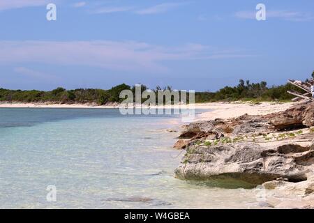 Paesaggio idilliaco di calma, acque costiere acque blu con assenza di onde e riva sabbiosa su di una spiaggia privata nelle Isole Turks e Caicos. Foto Stock