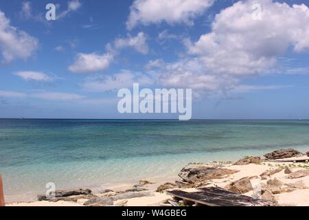 Idilliaco paesaggio marino di calma, acque costiere acque blu su di una spiaggia privata nelle Isole Turks e Caicos con puffy nuvole bianche sull'orizzonte. Foto Stock